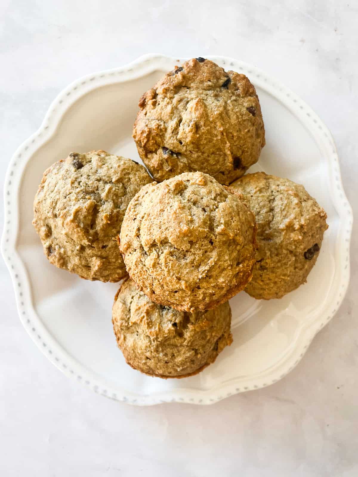 A decorative white plate with gluten free banana bread muffis.