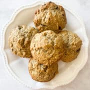 A decorative white plate with gluten free banana bread muffis.