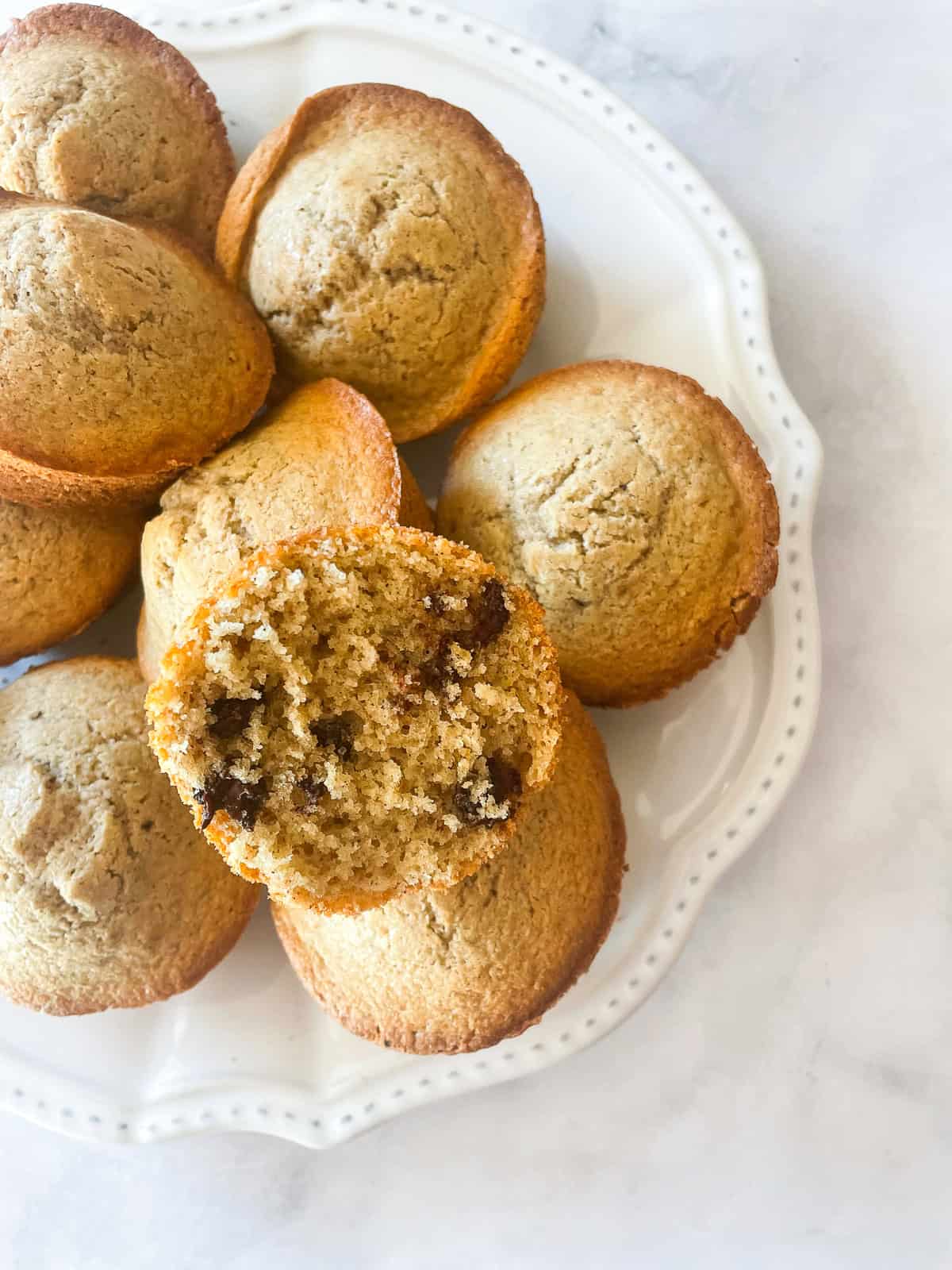 A chocolate chip muffin cut in half on top of muffin.