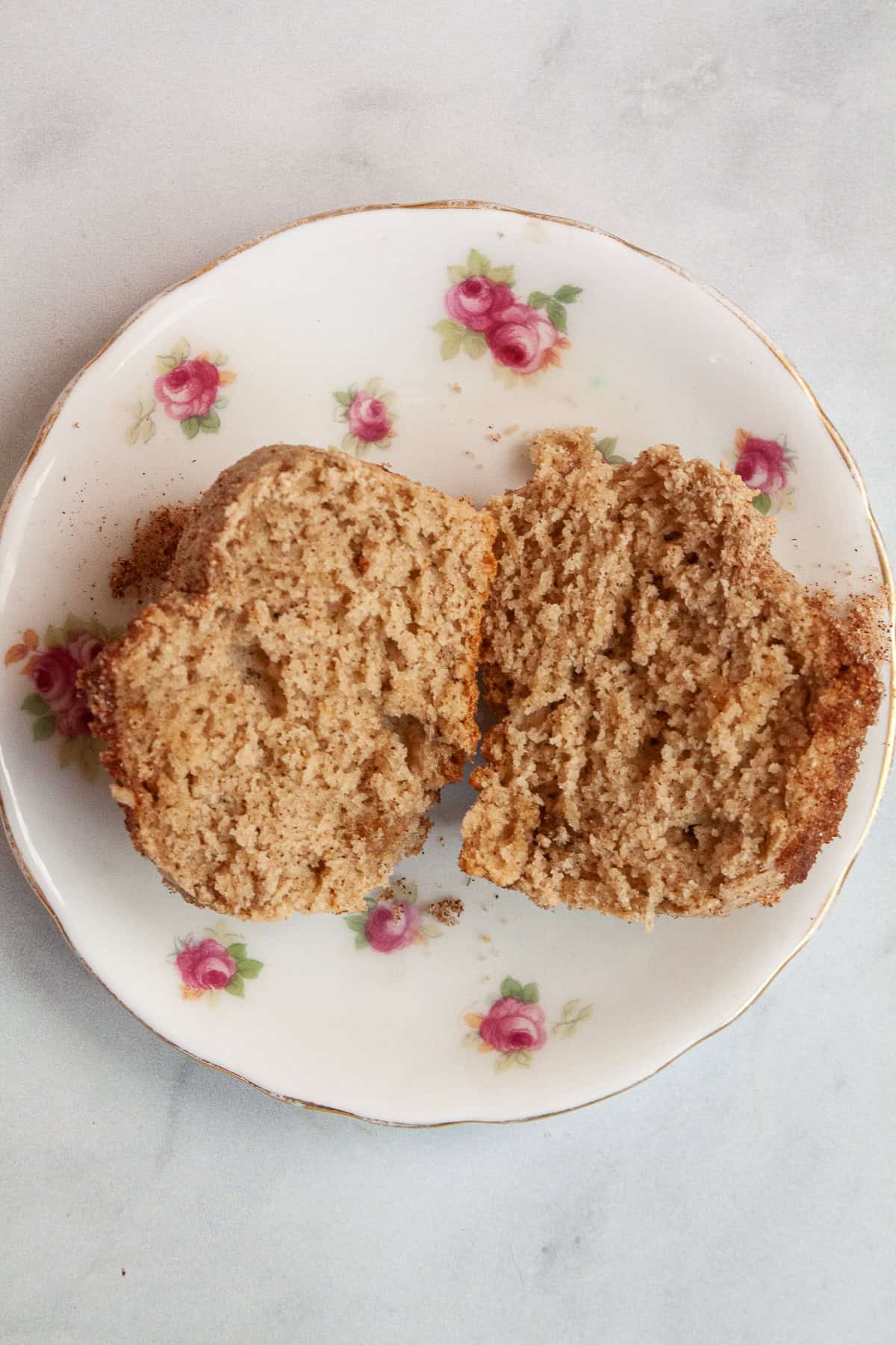 A cinnamon sugar muffin cut in half on a plate.