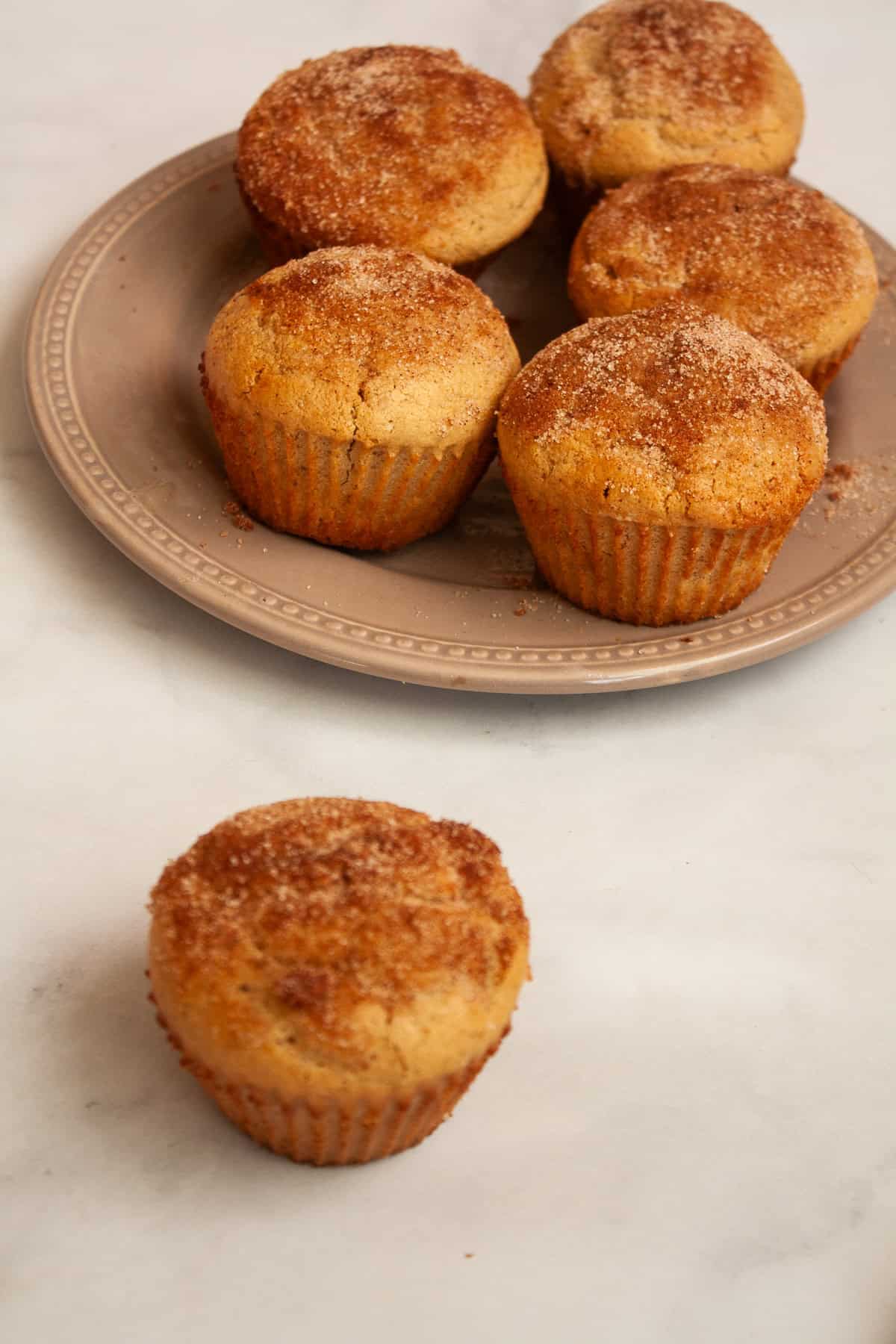 A plate of gluten free donut muffins and one on a counter.