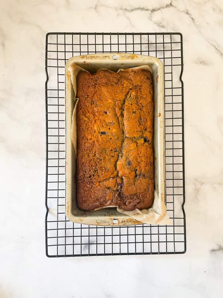 A loaf of blackberry banana bread cools in a pan.