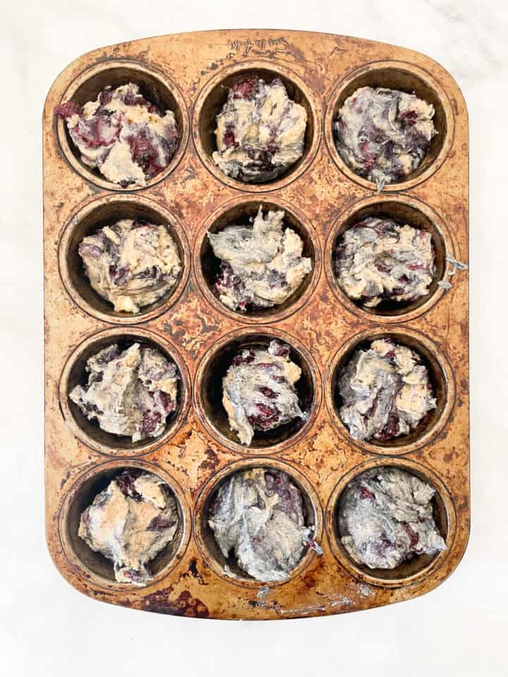 Banana blackberry muffin batter in a muffin tin.