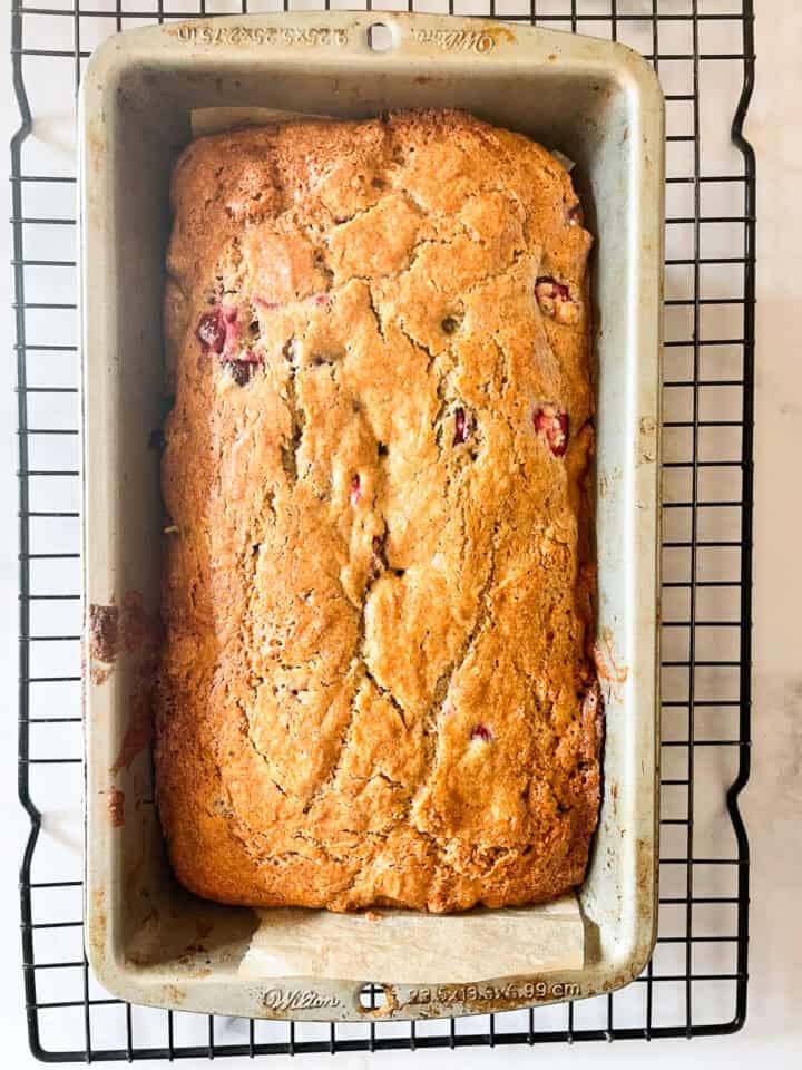 A loaf of gluten free cranberry walnut bread cools in the pan.