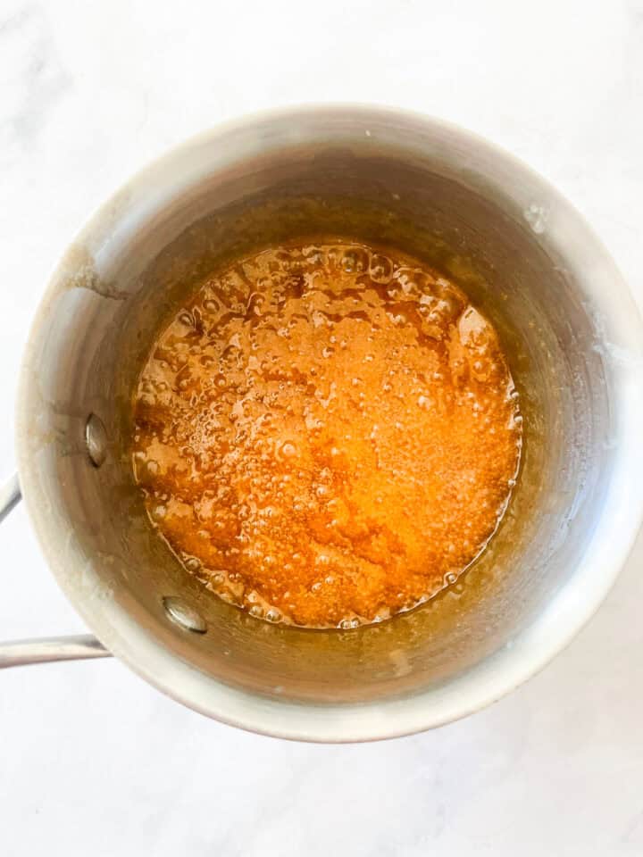 Maple syrup topping cooks until thick in a pot.