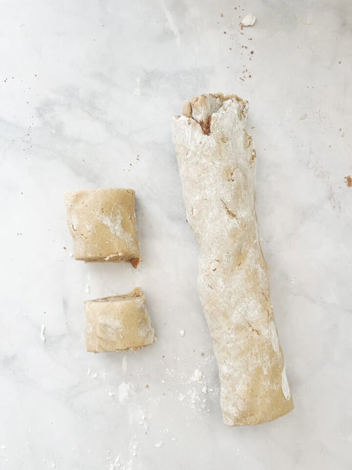 Cutting up a log of gluten-free cinnamon rolls dough.