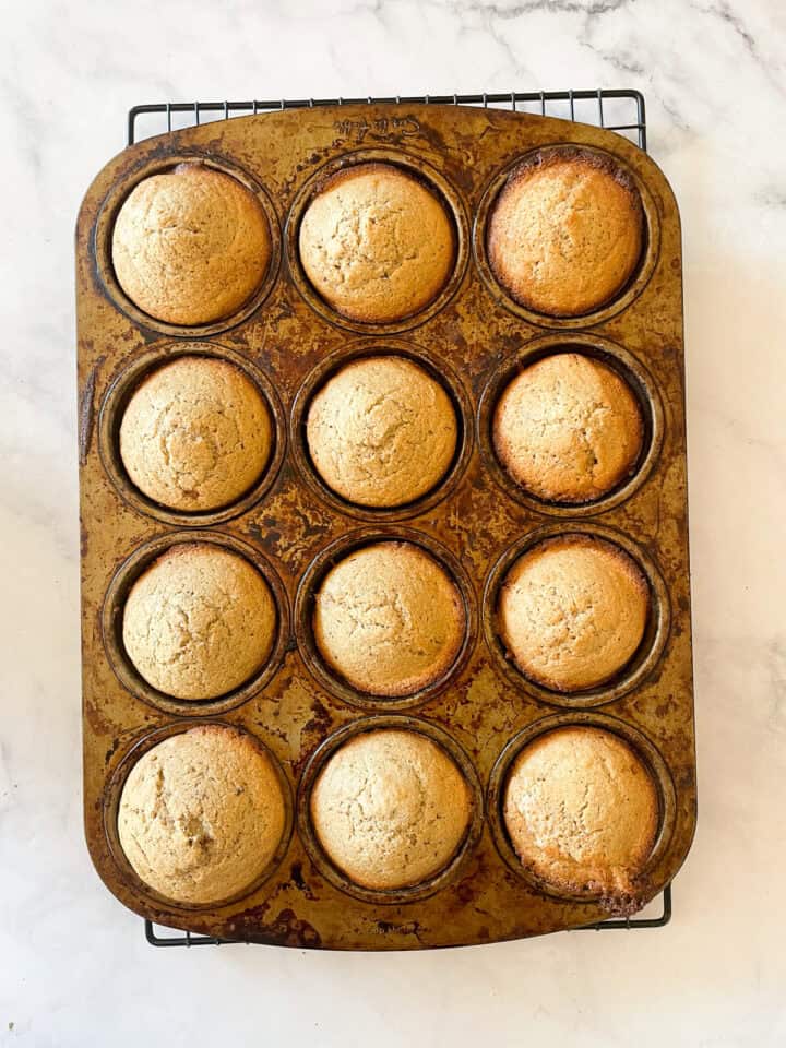 Cinnamon sugar muffins cool in a muffin tin.