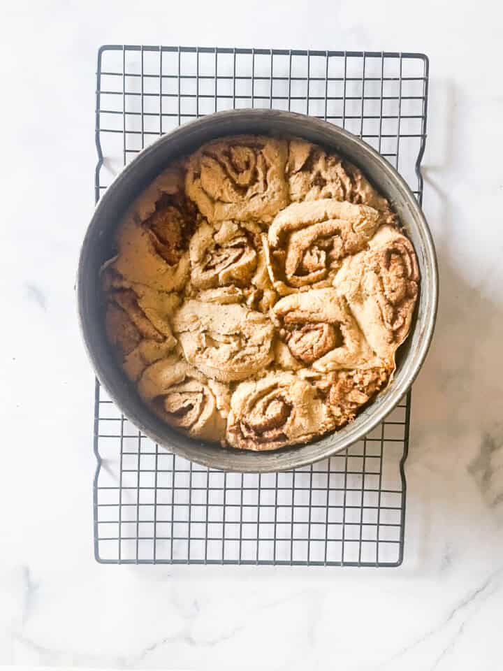 Oat flour cinnamon rolls cool in the pan on a rack.