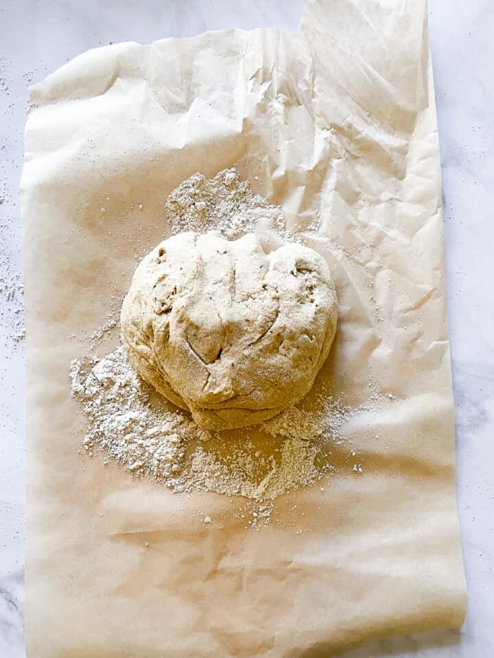 Dough for cinnamon rolls in a ball on a piece of parchment paper.