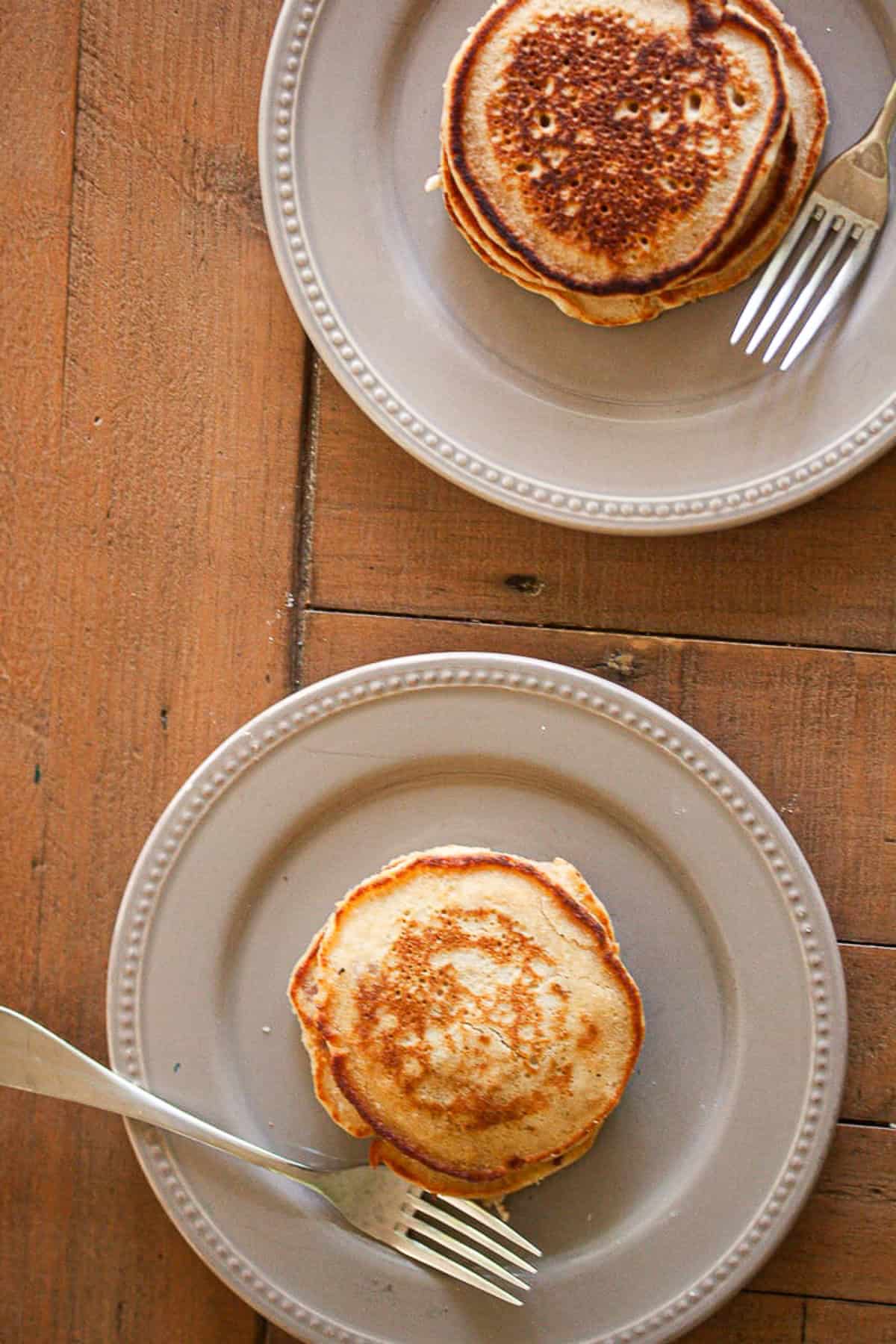 Two plates of oat flour pancakes and forks.