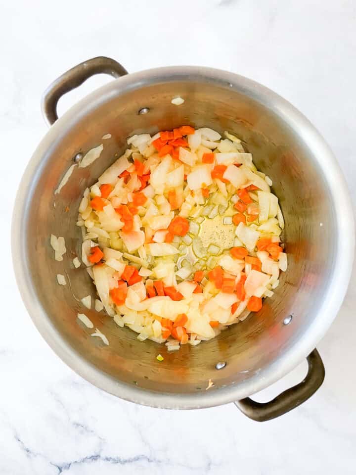 Onions, garlic, and carrots cook to make soup.