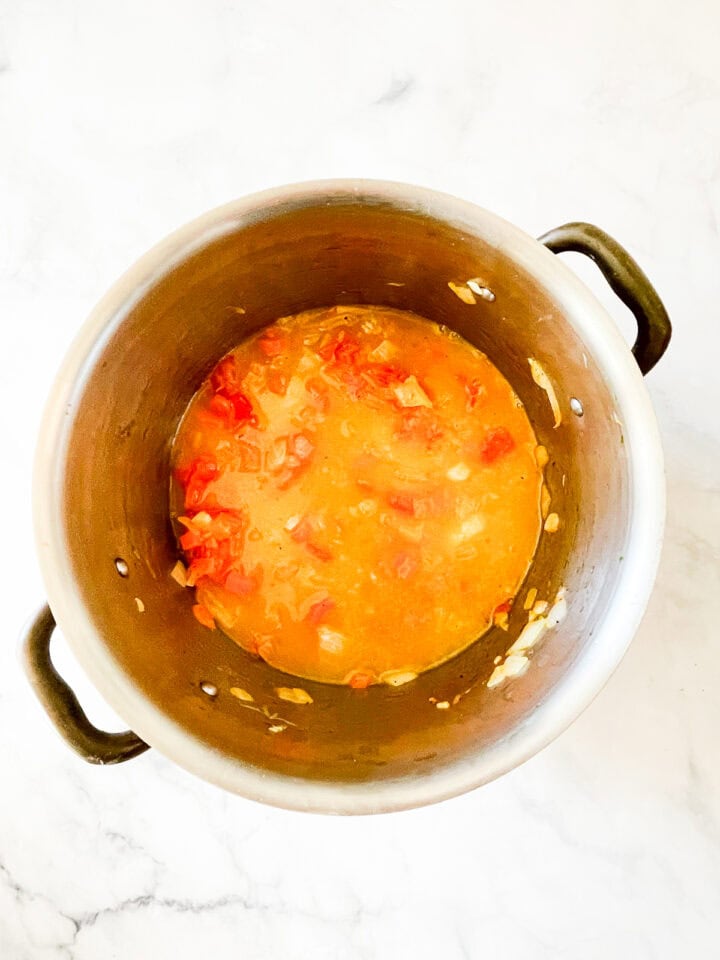 Minestrone soup simmers in a pot.