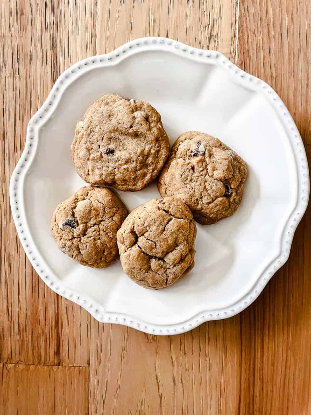 Four whole wheat chocolate chips cookies on a white plate.