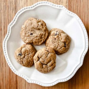 Four whole wheat chocolate chips cookies on a white plate.