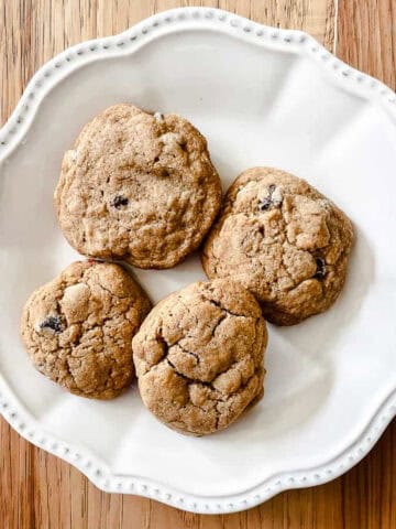 Four whole wheat chocolate chips cookies on a white plate.