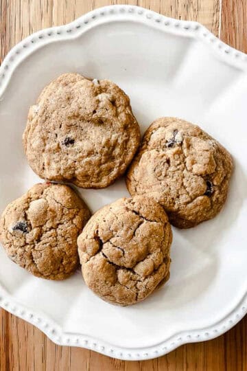 Four whole wheat chocolate chips cookies on a white plate.