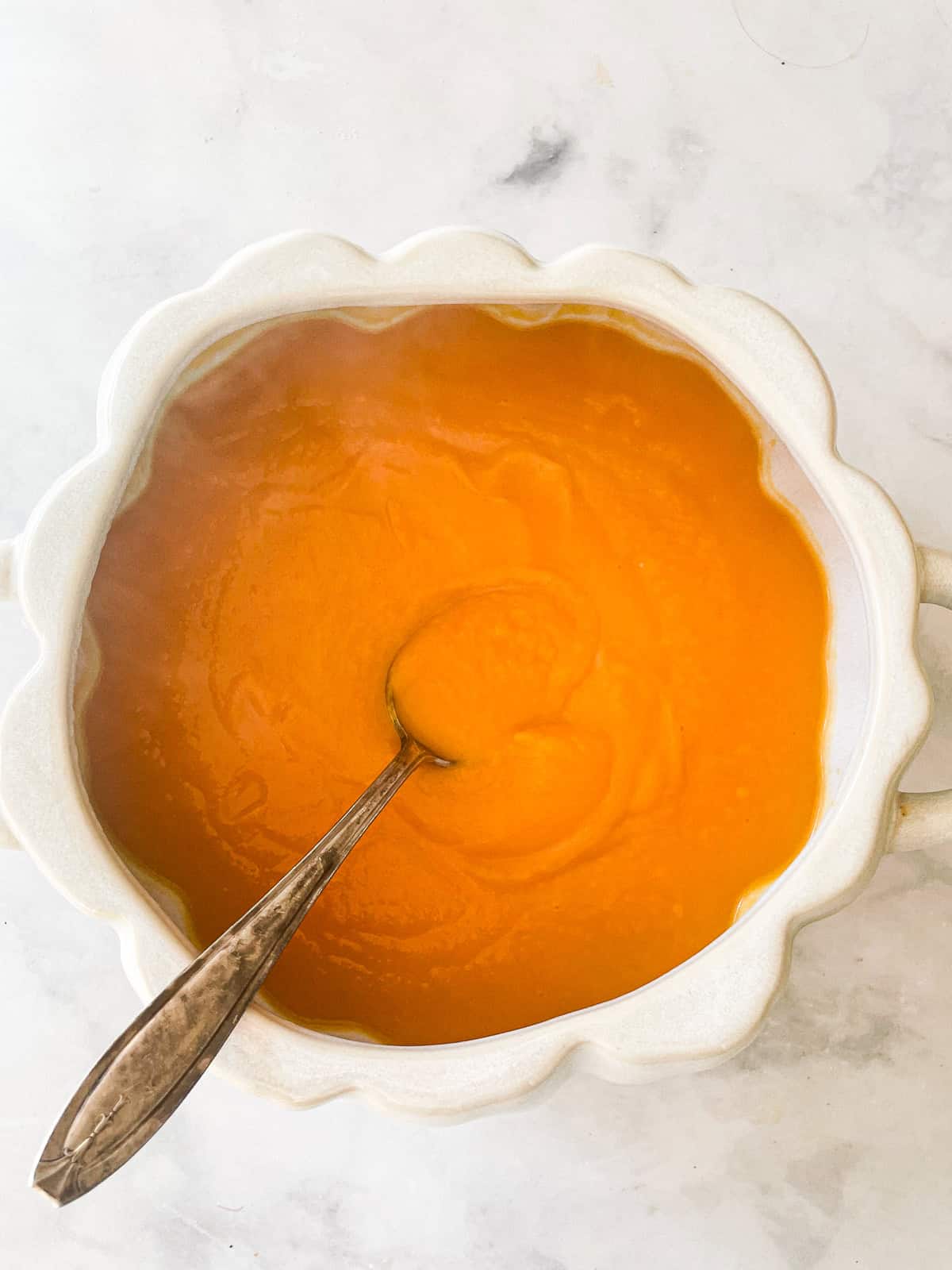 Tips for enjoying a gluten free Thanksgiving, plus lots of gluten free Thanksgiving recipes and ideas for the best meal ever! A white serving dish with butternut squash puree and a spoon.