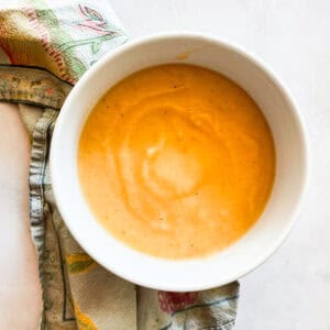 A bowl of carrot cauliflower soup on a napkin.