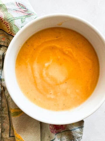 A bowl of carrot cauliflower soup on a napkin.