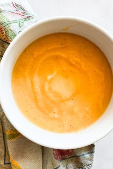 A bowl of carrot cauliflower soup on a napkin.