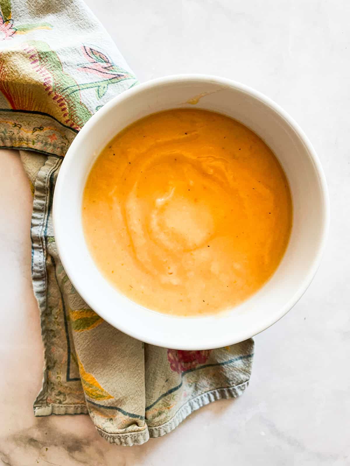 A bowl of carrot cauliflower soup on a napkin.