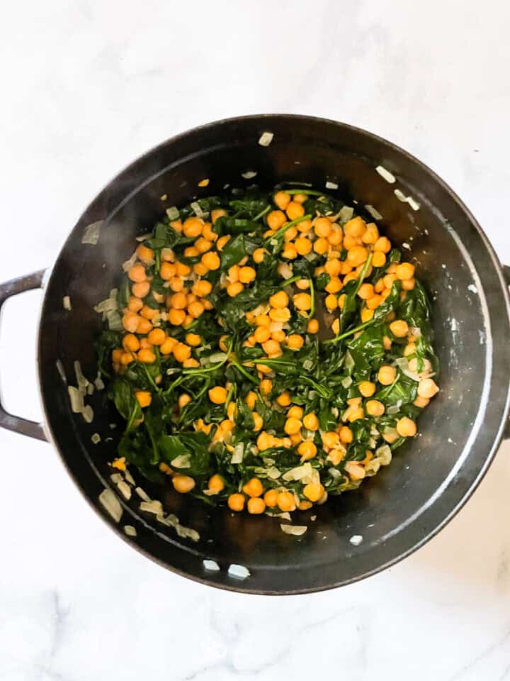 Spinach cooks with chickpeas in a pot.