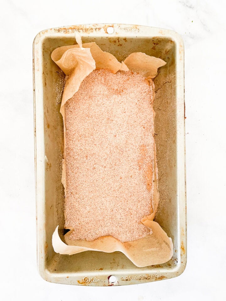 Cinnamon sugar added to batter in a loaf pan.