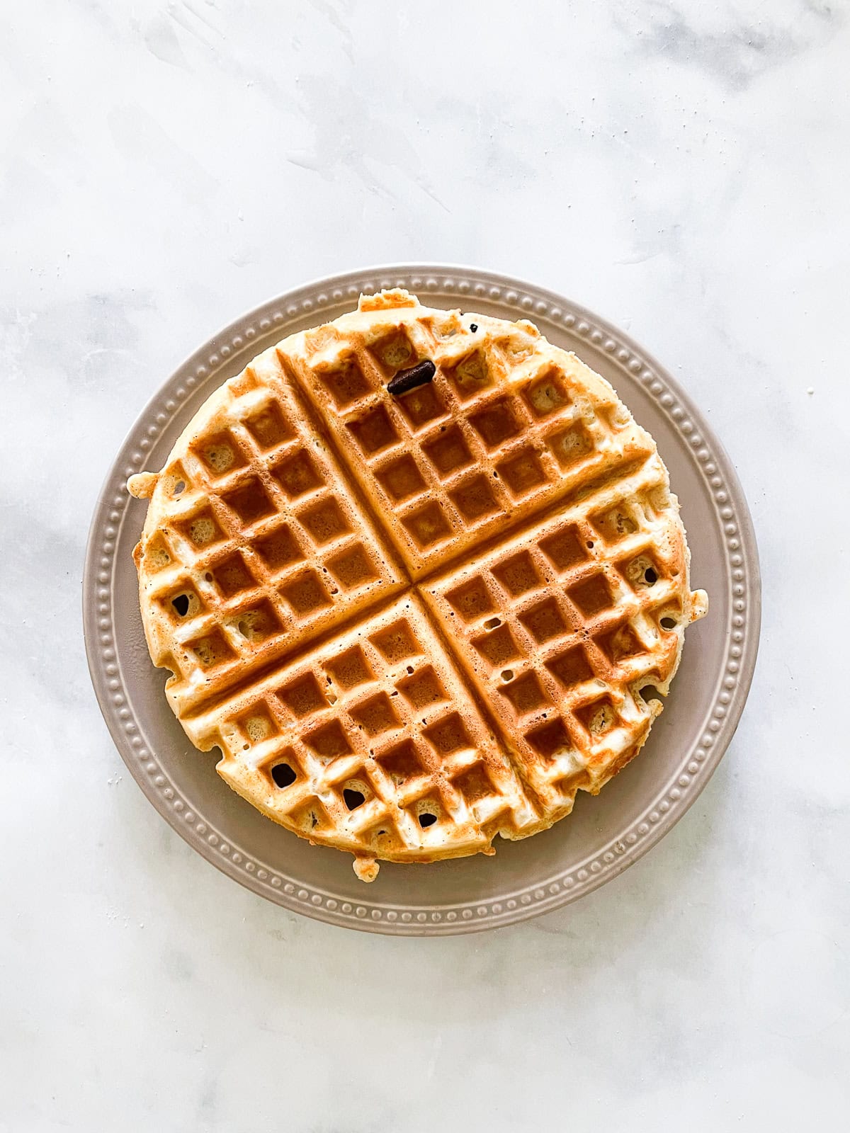 A waffle topped with syrup on a plate.