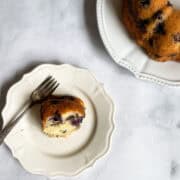A slice of plated blueberry yogurt cake and the cake next to it.