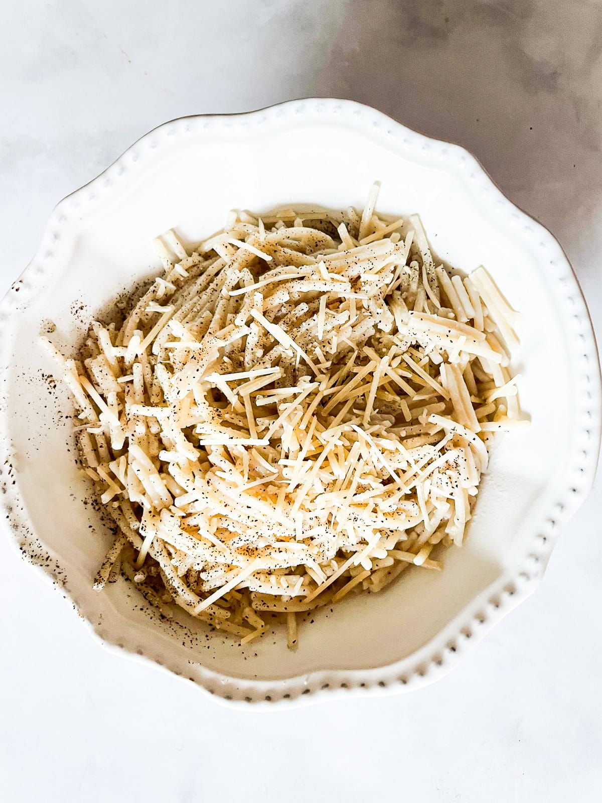 A white bowl full of cheesy pasta.