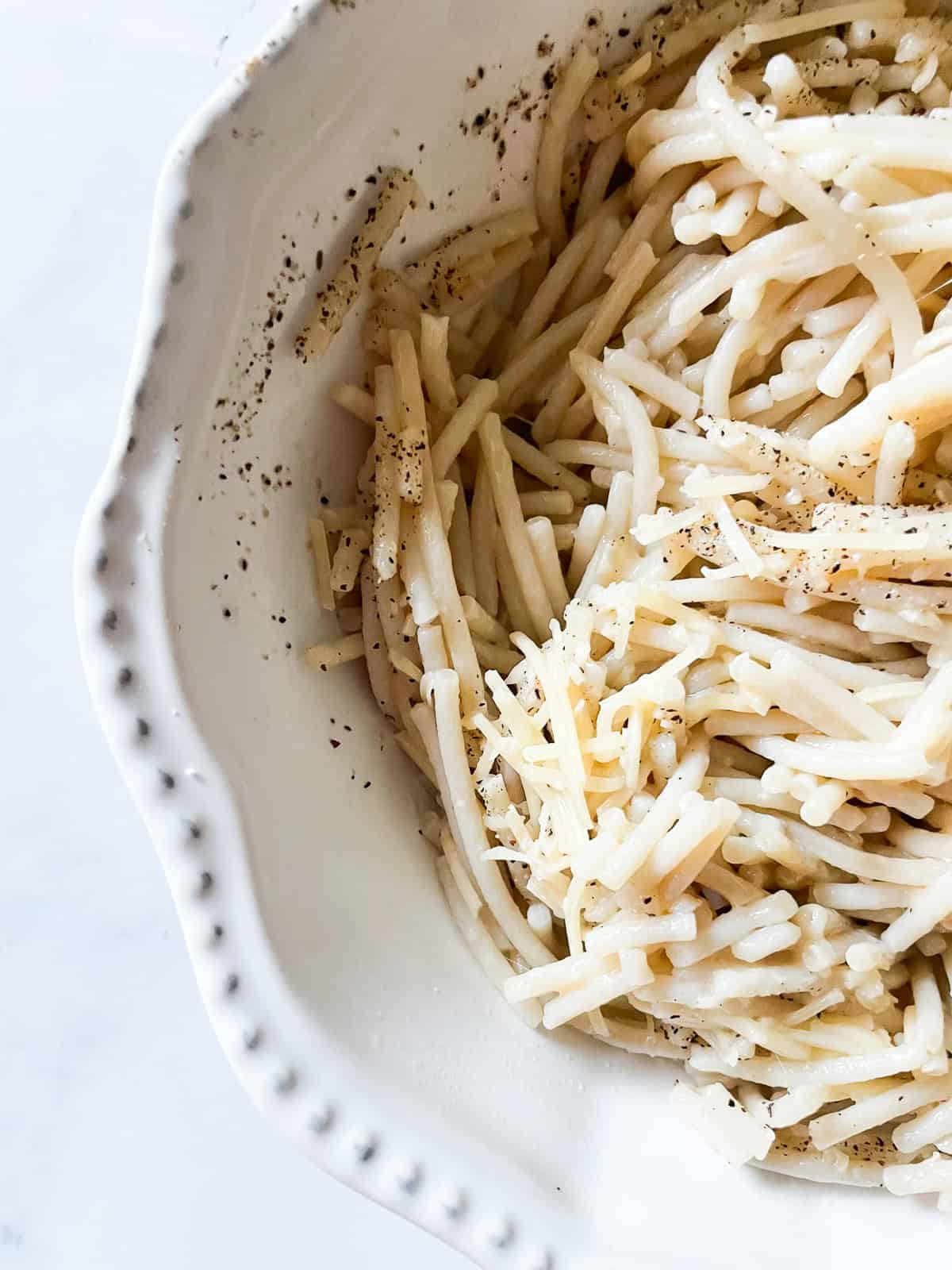 A bowl of cheesy pasta topped with cheese.