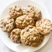 A white plate full of gluten free oatmeal chocolate chip cookies.