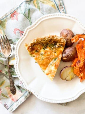 A plate of gluten free quiche and roasted vegetables on a napkin.