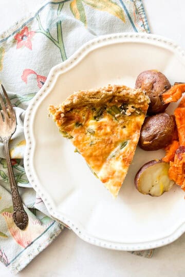A plate of gluten free quiche and roasted vegetables on a napkin.