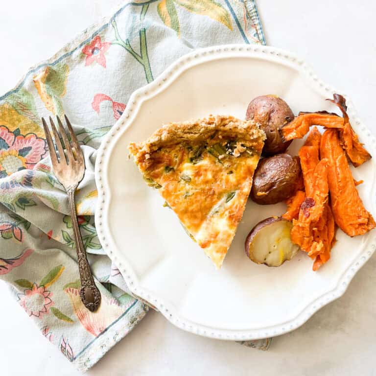 A plate of gluten free quiche and roasted vegetables on a napkin.
