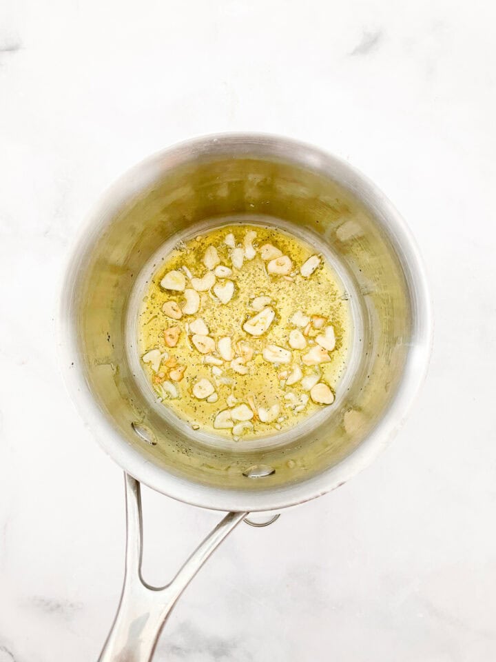 Garlic sautees in olive oil in a pot.