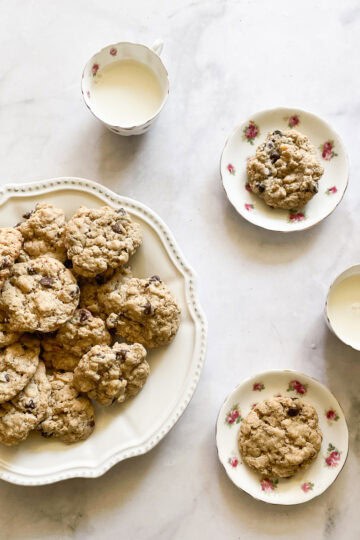 Cups of milk and plates of chocolate chip and walnut cookies.