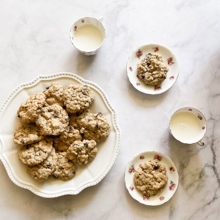 Cups of milk and plates of chocolate chip and walnut cookies.
