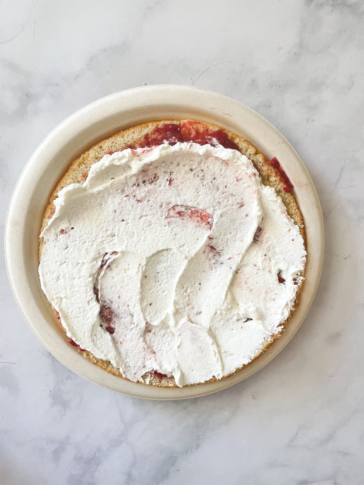 A gluten free berries and cream cake is layered with sweet whipped cream, sliced strawberries, and juicy blueberries. Whipped cream tops strawberries.