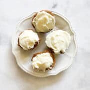 A plate holds four gluten free carrot cake cupcakes.
