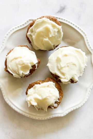 A plate holds four gluten free carrot cake cupcakes.