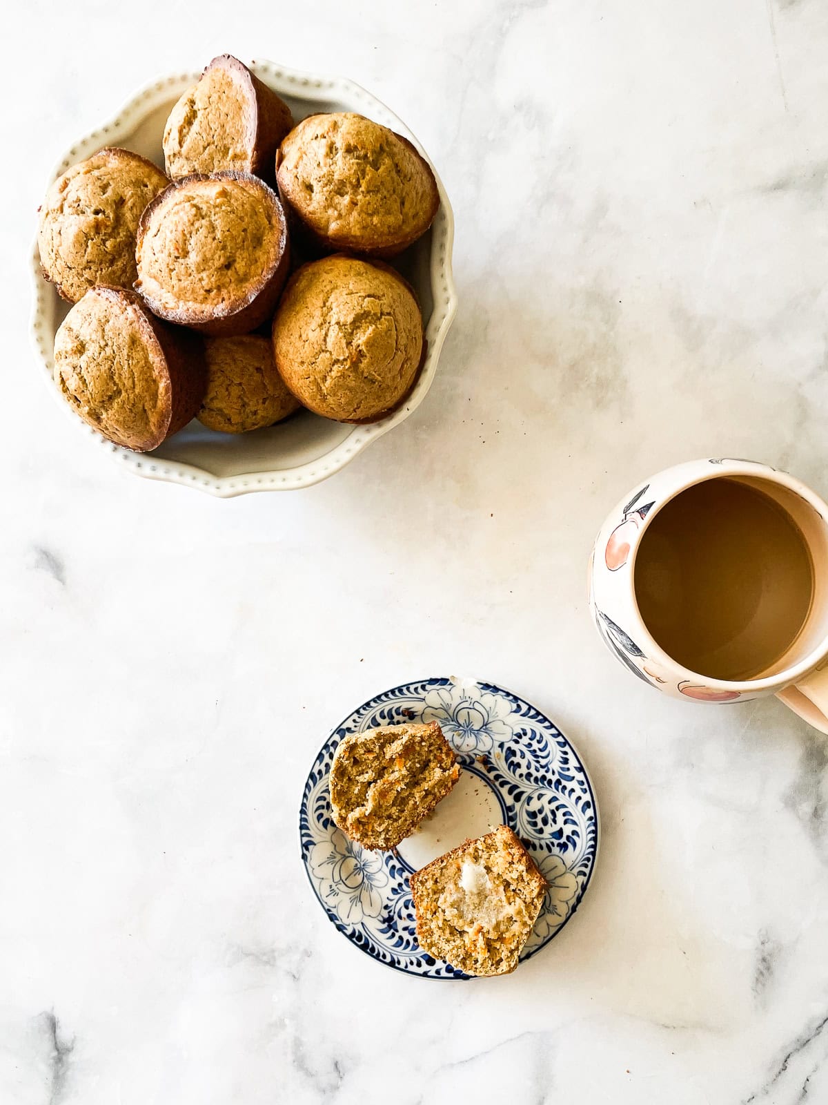 A bowl of gluten free carrot muffins, a cup of coffee, and a muffin on a plate.