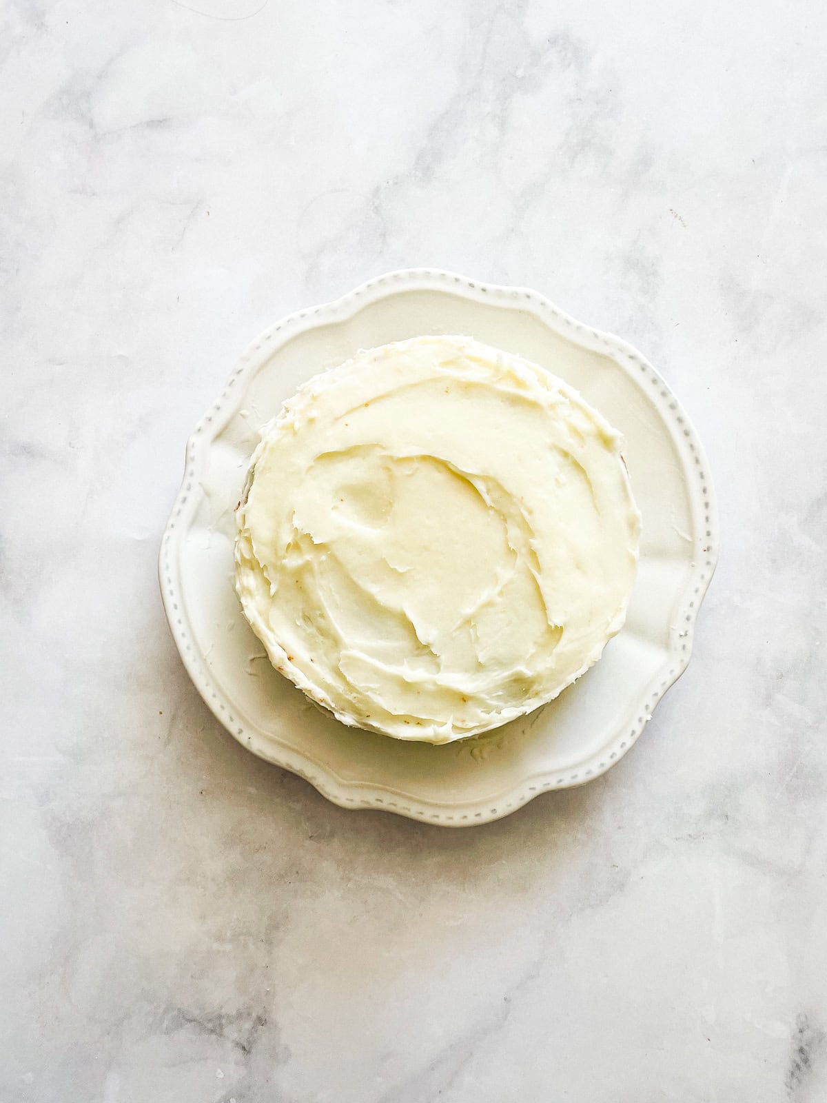 A frosted gluten free mini carrot cake on a plate.