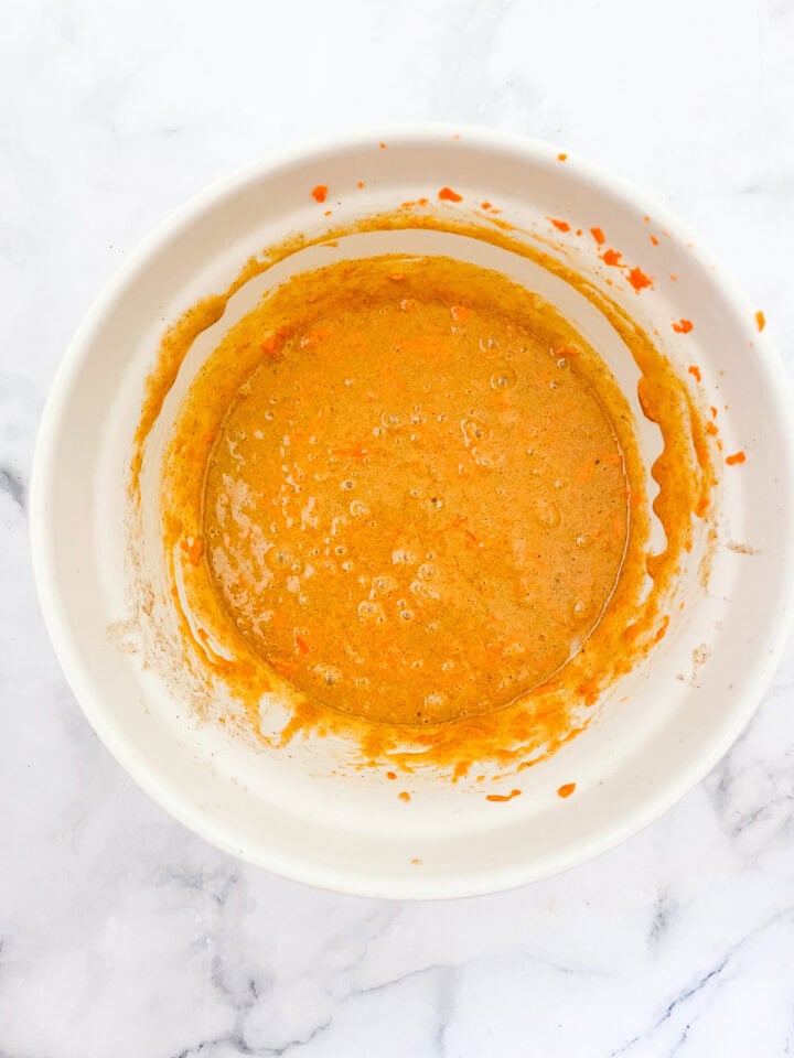 Carrots are added to cupcake batter in a bowl.