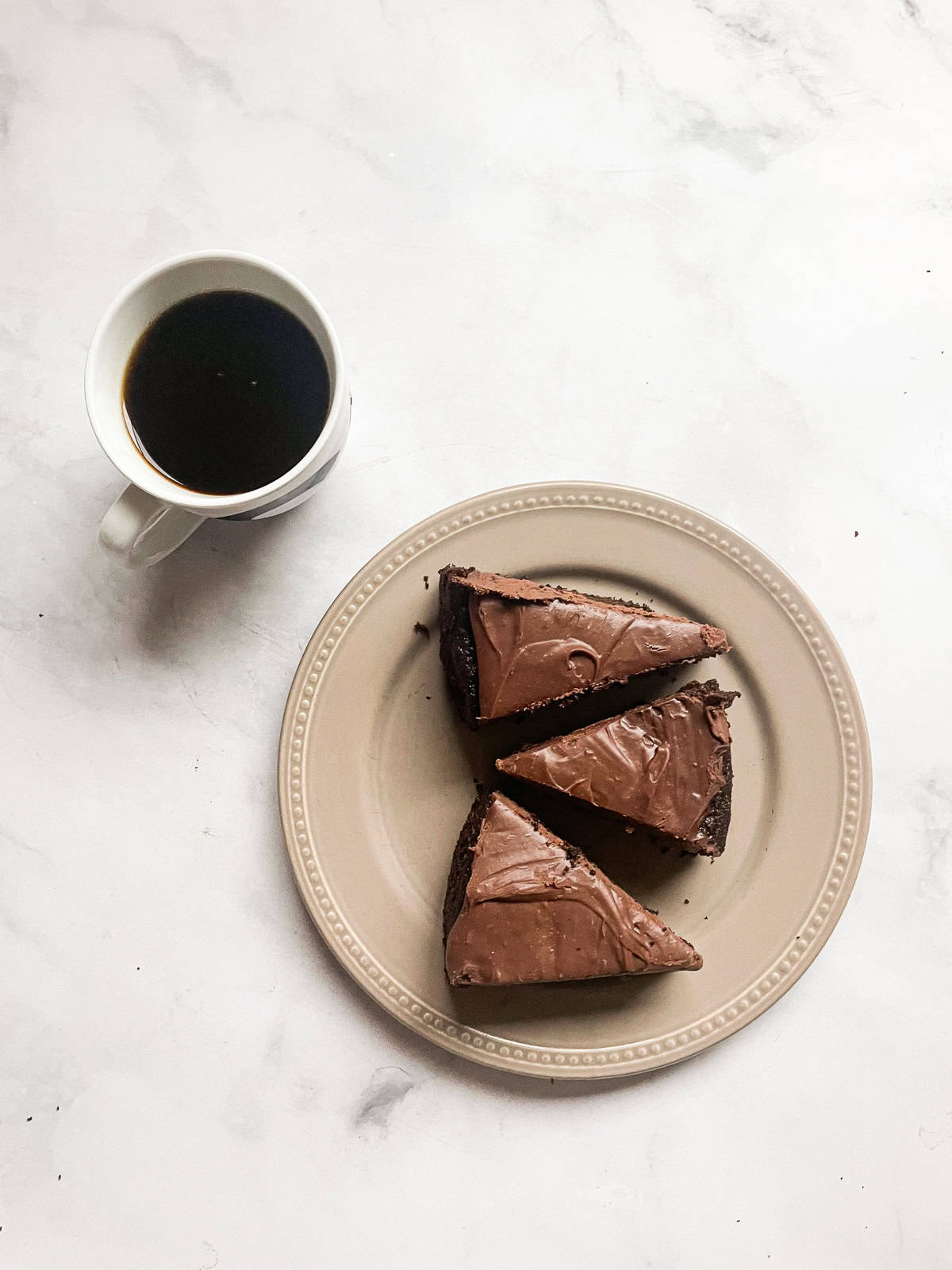 Slices of chocolate teff cake on a plate with a cup of coffee.