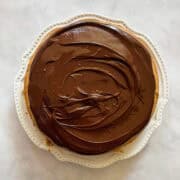 A gluten free banana cake with chocolate icing on a plate.