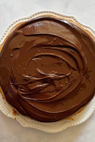 A gluten free banana cake with chocolate icing on a plate.
