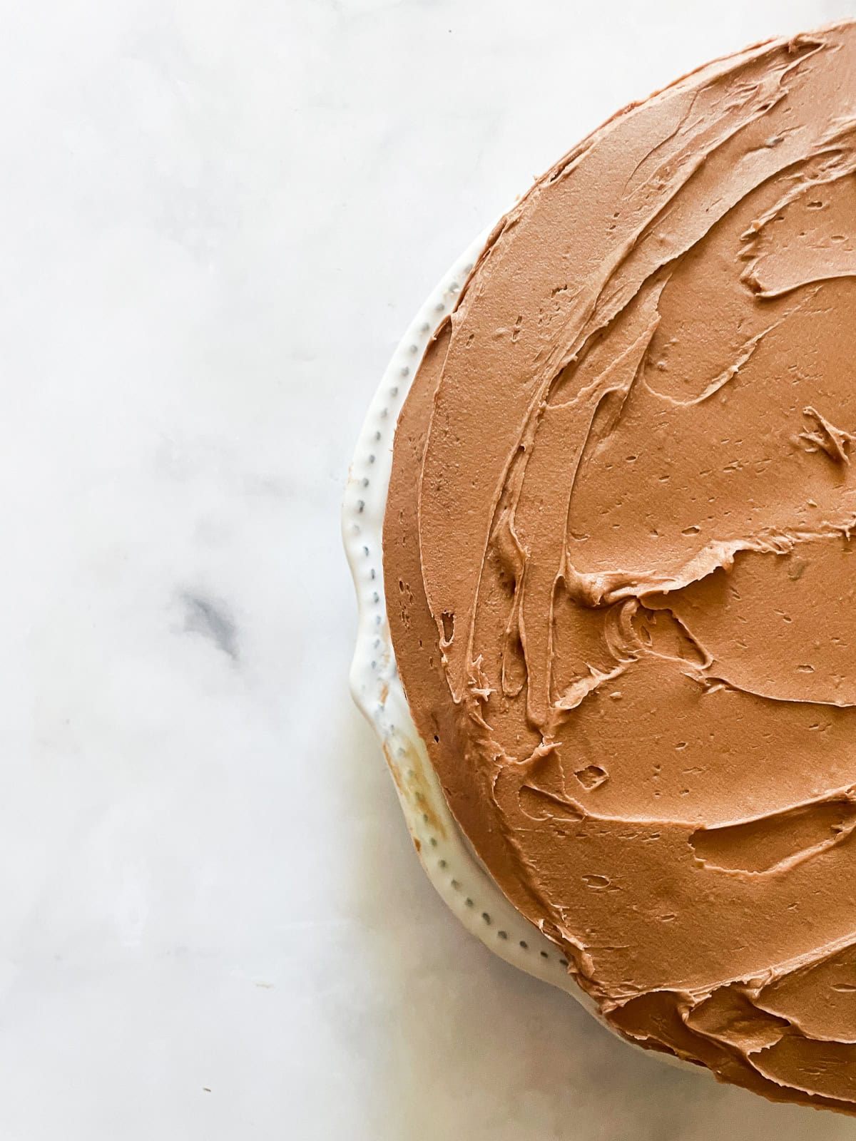 This beautiful gluten-free birthday cake recipe features velvety vanilla cake layers filled and frosted with chocolate buttercream frosting Half of a gluten-free birthday cake.