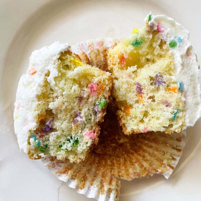 A gluten free funfetti cupcake cut in half on a plate.