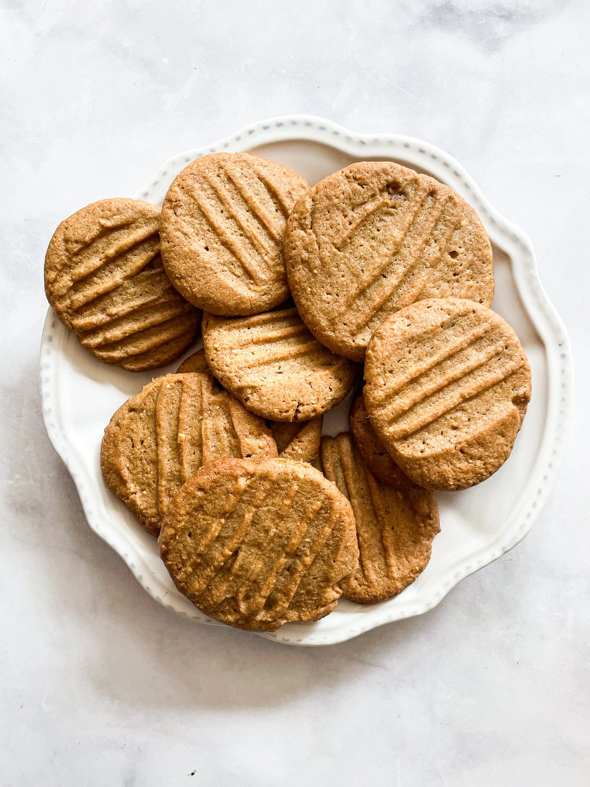 Tender and super peanut buttery gluten-free peanut butter cookies are made in just one bowl! Packed with sweet-salty flavor in every bite. Gluten-free peanut butter cookies on a white plate.